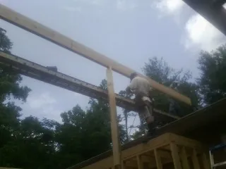 Carpenter setting a ridge beam over a new addition frame — Ice Dam Removal by Roofing Brothers in Syosset
