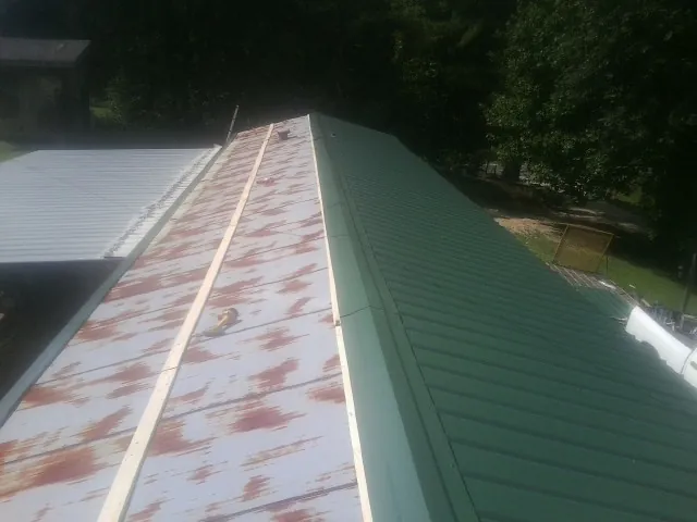 Old rusted panels beside newly installed green metal roofing — Wind Damage Roof Repair by Roofing Brothers in Syosset