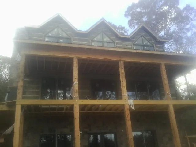 Dormers and porch framing on a large log home under construction — Roof Coating work by our crew in Syosset