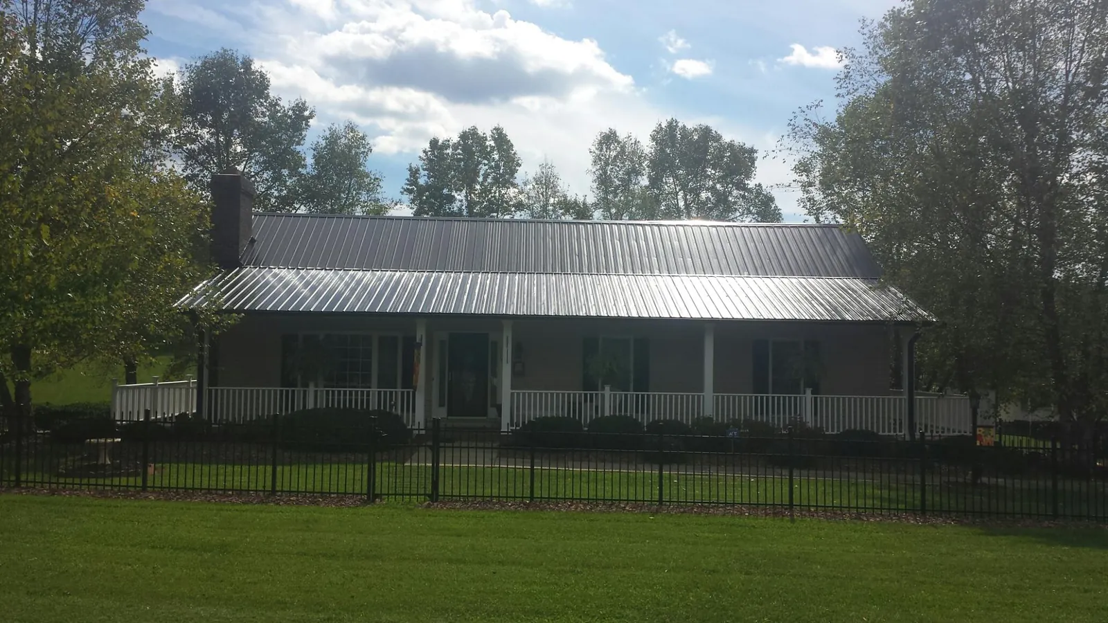 Gray metal roof on a brick ranch with a full width front porch — Gutter Guard Installation work by our crew in Syosset