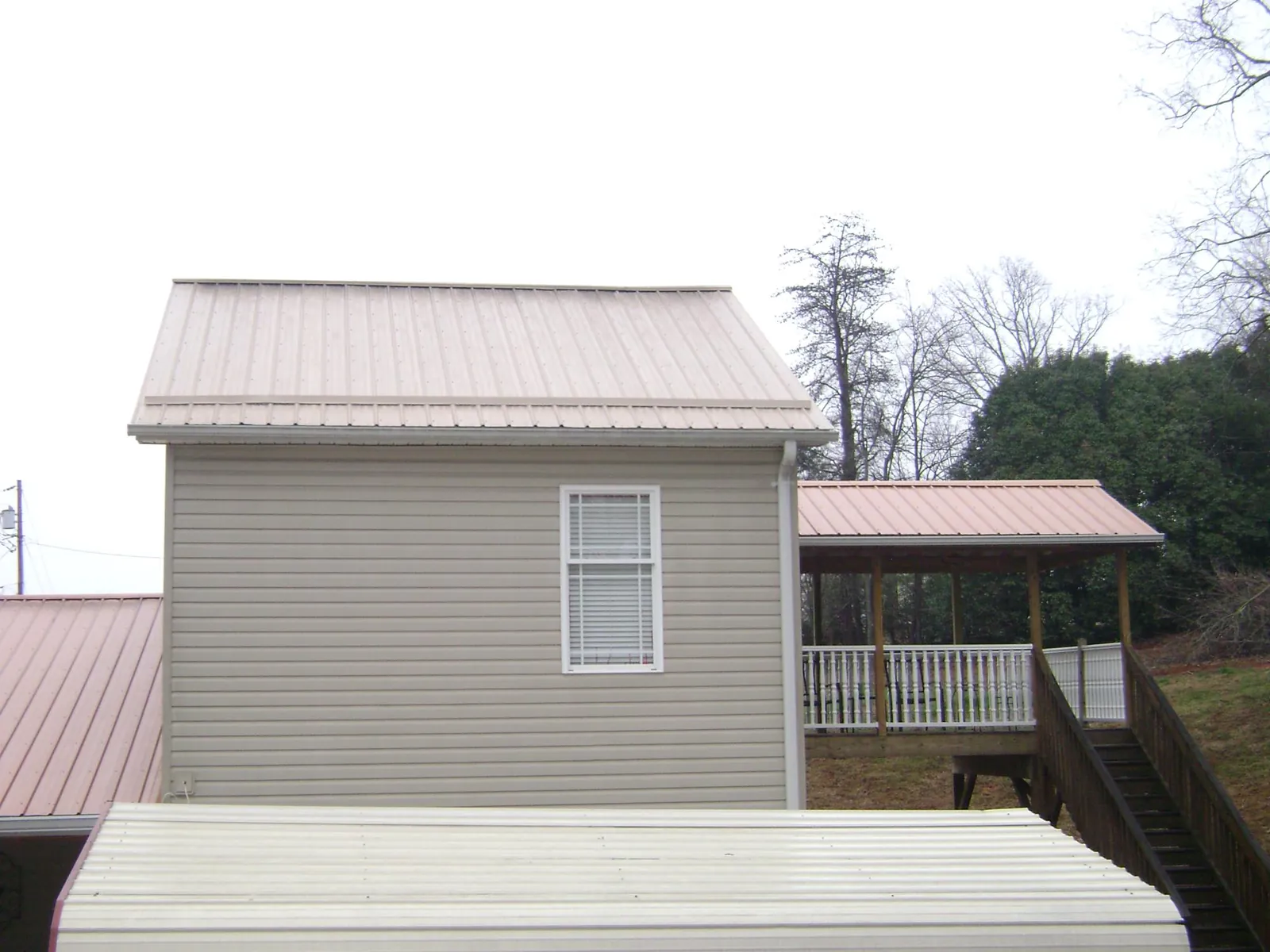 Tan metal roofs on a two story addition and attached porch, from a Roof Replacement job in Syosset
