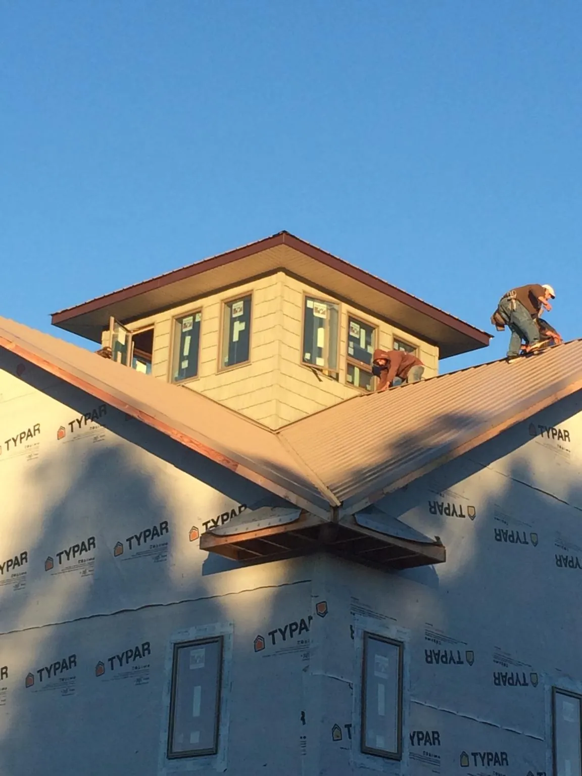 Roofers working around a rooftop cupola on a new metal roof at sunset — Roof Waterproofing in Syosset by Roofing Brothers